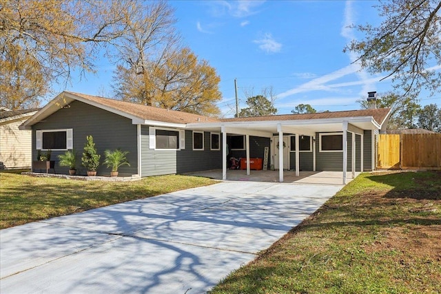 single story home featuring fence, a yard, a chimney, concrete driveway, and a carport