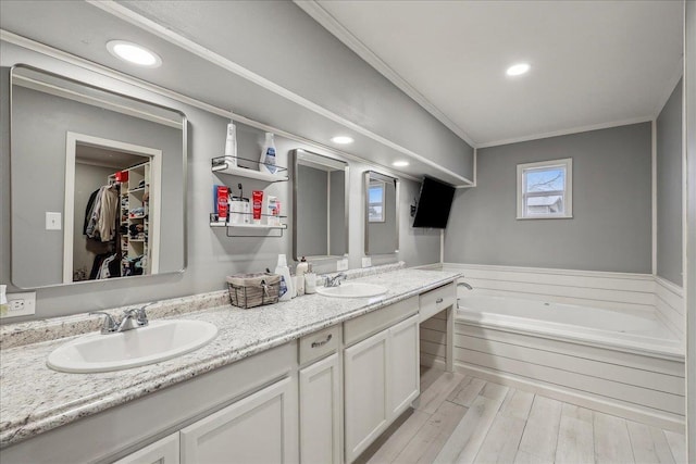 full bath featuring double vanity, ornamental molding, wood finished floors, and a sink