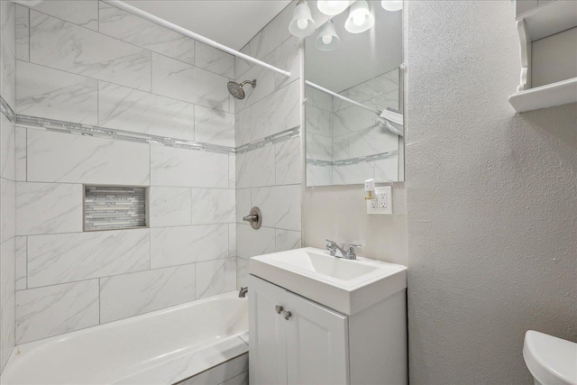 bathroom with vanity, bathing tub / shower combination, toilet, and a textured wall