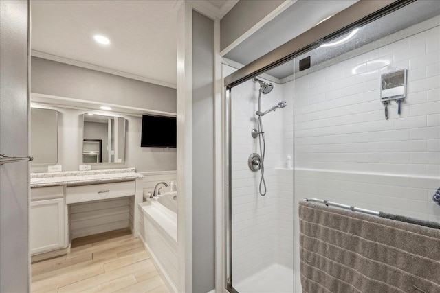 bathroom featuring vanity, a garden tub, wood finished floors, a shower stall, and crown molding