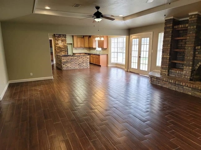 unfurnished living room with a tray ceiling, ceiling fan, dark hardwood / wood-style flooring, and a fireplace