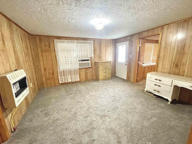 interior space with carpet flooring, a textured ceiling, heating unit, and wood walls