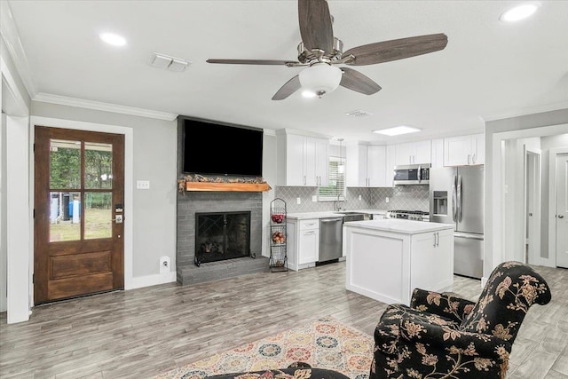 kitchen with a kitchen island, appliances with stainless steel finishes, tasteful backsplash, light hardwood / wood-style floors, and white cabinetry