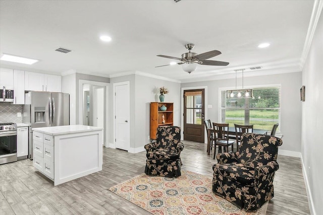 kitchen featuring decorative backsplash, appliances with stainless steel finishes, pendant lighting, white cabinetry, and a kitchen island