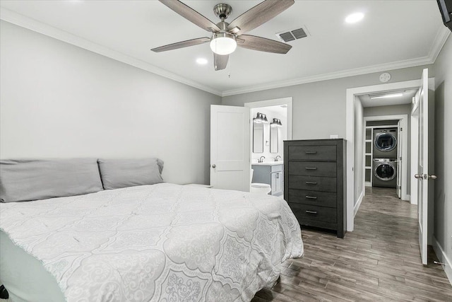 bedroom featuring ensuite bathroom, ceiling fan, crown molding, hardwood / wood-style floors, and stacked washer / drying machine