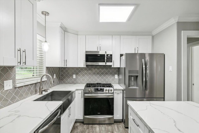 kitchen featuring white cabinets, sink, appliances with stainless steel finishes, decorative light fixtures, and light stone counters