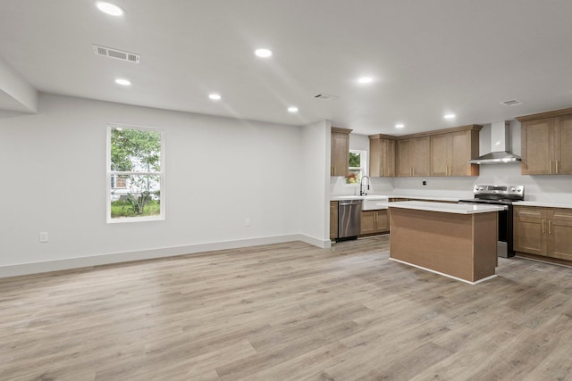 3266 Brent Dr, Orange, TX 77632 - kitchen featuring wall chimney range hood, stainless steel appliances, light countertops, light wood-style floors, and a center island