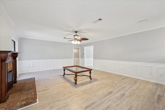 100 Teakwood St, Silsbee, TX 77656 - unfurnished room with crown molding, ceiling fan, a brick fireplace, light wood finished floors, and wainscoting