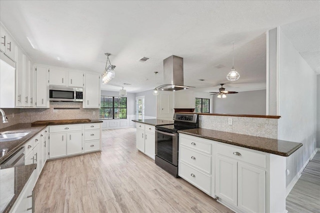 100 Teakwood St, Silsbee, TX 77656 - kitchen with stainless steel appliances, island range hood, a ceiling fan, white cabinetry, and light wood-type flooring