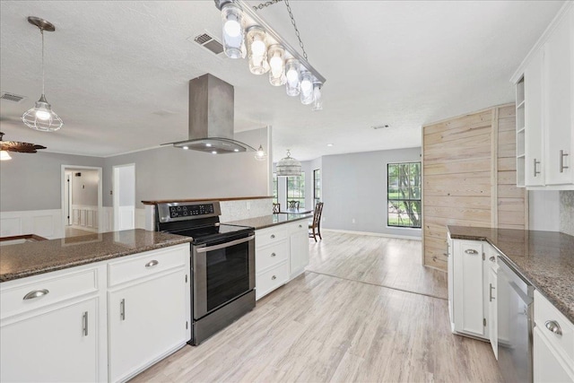 100 Teakwood St, Silsbee, TX 77656 - kitchen featuring appliances with stainless steel finishes, island range hood, open floor plan, white cabinetry, and wainscoting