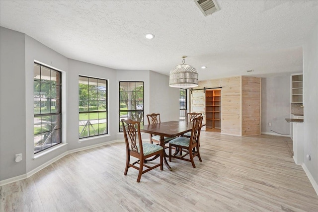 100 Teakwood St, Silsbee, TX 77656 - dining space featuring a textured ceiling, light wood-style flooring, a barn door, and recessed lighting