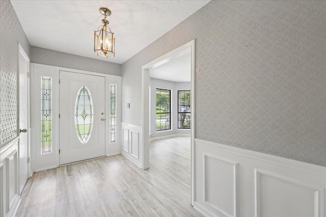 100 Teakwood St, Silsbee, TX 77656 - foyer entrance featuring a chandelier, light wood-type flooring, wainscoting, wallpapered walls, and a decorative wall