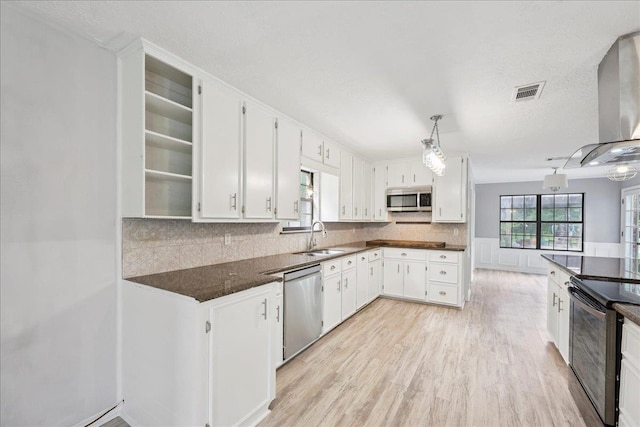 100 Teakwood St, Silsbee, TX 77656 - kitchen featuring stainless steel appliances, extractor fan, light wood-style flooring, decorative backsplash, and a textured ceiling