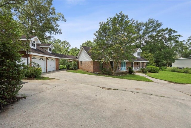 100 Teakwood St, Silsbee, TX 77656 - view of front of property with concrete driveway, brick siding, covered porch, a front lawn, and an attached garage