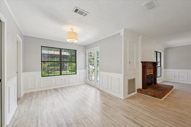 100 Teakwood St, Silsbee, TX 77656 - unfurnished living room with a decorative wall, a textured ceiling, wood finished floors, crown molding, and wainscoting