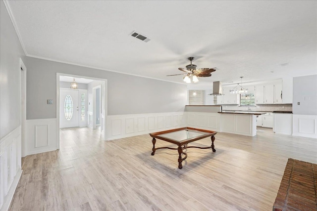 100 Teakwood St, Silsbee, TX 77656 - unfurnished living room with a decorative wall, ceiling fan, crown molding, wainscoting, and light wood-style floors
