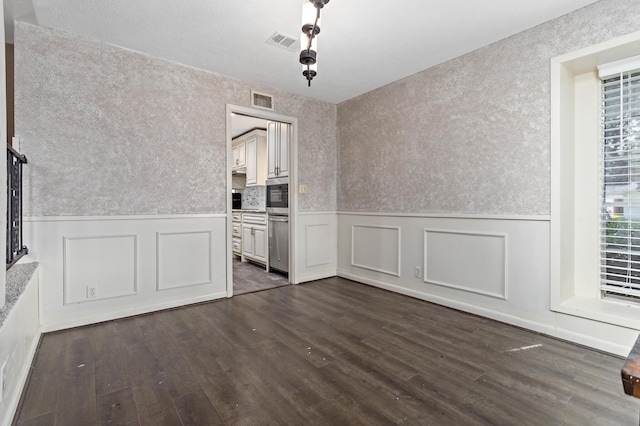 unfurnished dining area with wallpapered walls, visible vents, and dark wood finished floors