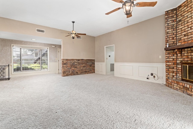 unfurnished living room with visible vents, wainscoting, ceiling fan, carpet floors, and a fireplace