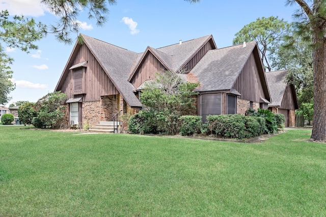 view of front of home with a shingled roof, brick siding, and a front lawn