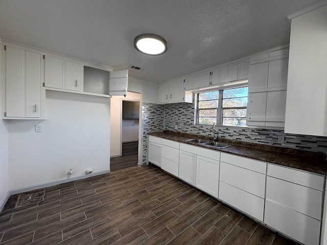 kitchen with tasteful backsplash, sink, and white cabinets