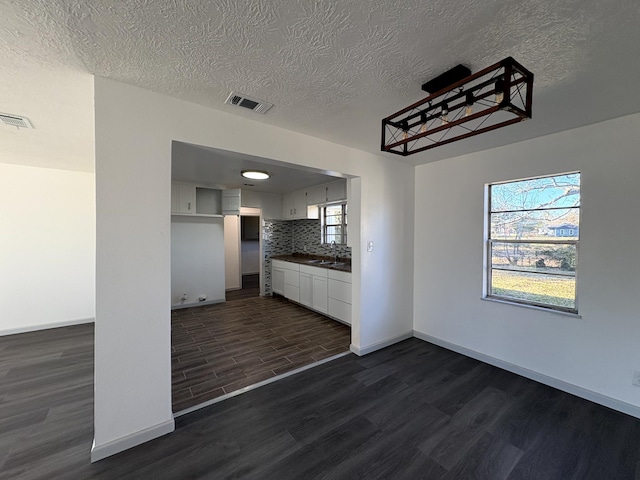 kitchen featuring sink, white cabinetry, backsplash, a textured ceiling, and dark hardwood / wood-style flooring