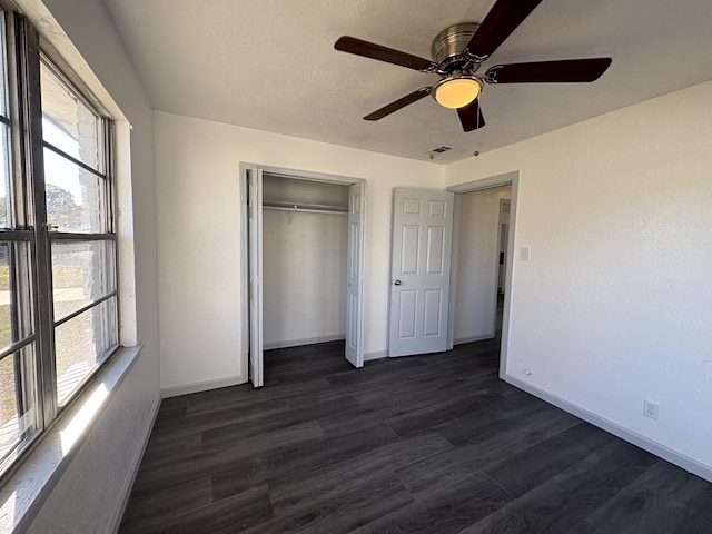 unfurnished bedroom featuring dark wood-type flooring, ceiling fan, a closet, and a textured ceiling