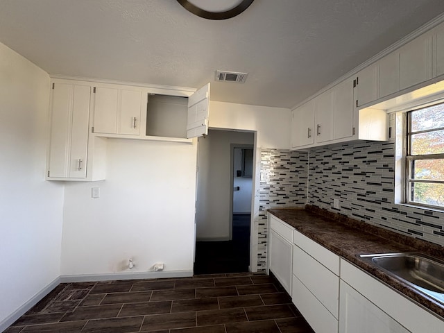 kitchen with tasteful backsplash, white cabinetry, and sink