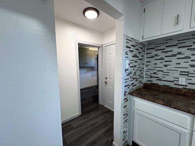 kitchen with dark hardwood / wood-style flooring, dark stone countertops, white cabinets, and backsplash