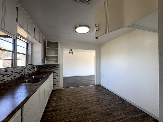 kitchen featuring tasteful backsplash, sink, white cabinetry, and a textured ceiling