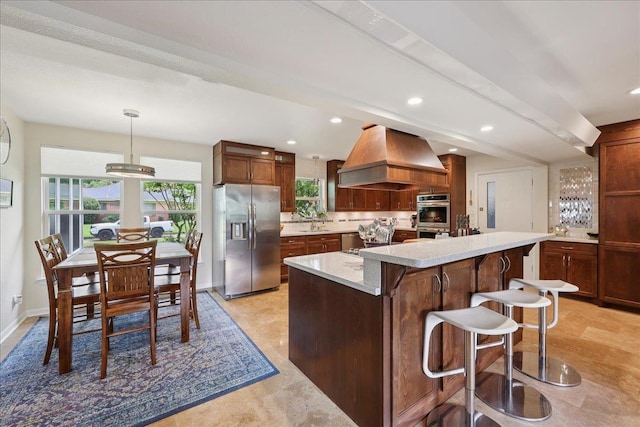 5775 Clinton St, Beaumont, TX 77706 - kitchen featuring appliances with stainless steel finishes, custom exhaust hood, light countertops, decorative backsplash, and a breakfast bar area