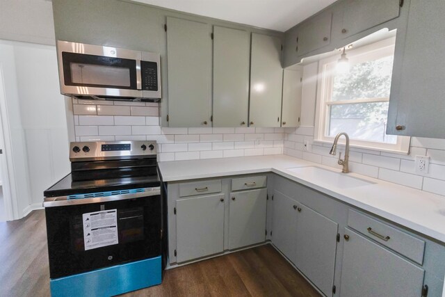 kitchen featuring gray cabinetry, sink, dark hardwood / wood-style floors, decorative backsplash, and appliances with stainless steel finishes