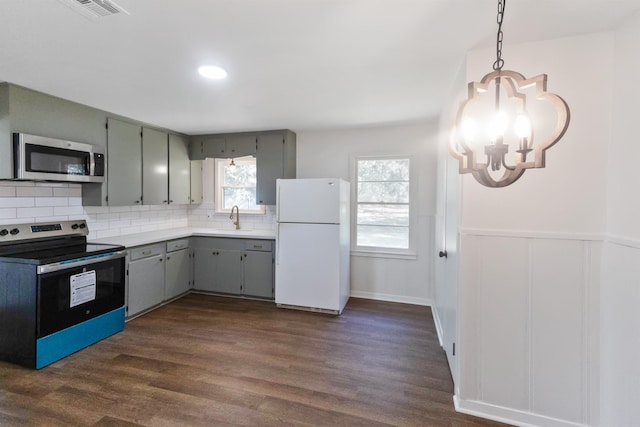 kitchen with an inviting chandelier, sink, decorative backsplash, gray cabinets, and appliances with stainless steel finishes