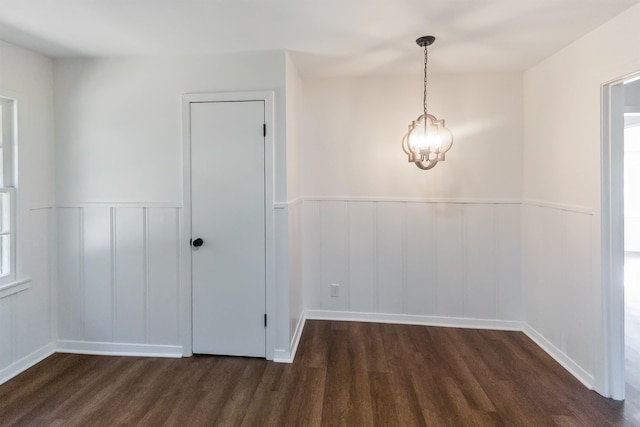 unfurnished room with an inviting chandelier and dark wood-type flooring