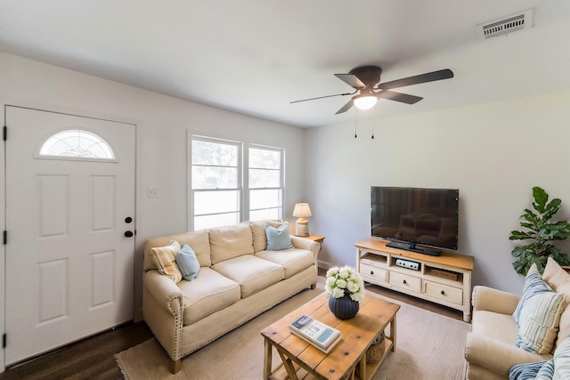 living room with dark wood-type flooring, ceiling fan, and a healthy amount of sunlight