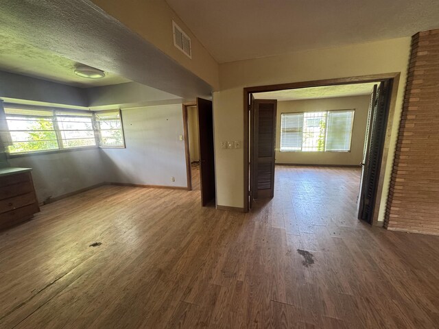2595 Beech St, Beaumont, TX 77702 - empty room with wood finished floors, plenty of natural light, and a textured ceiling