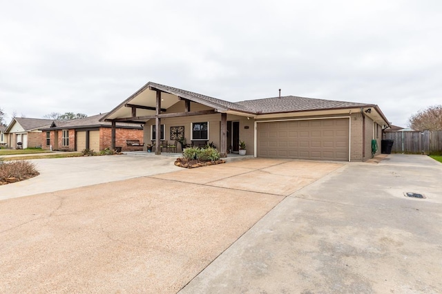 view of front of home featuring brick siding, driveway, an attached garage, and fence