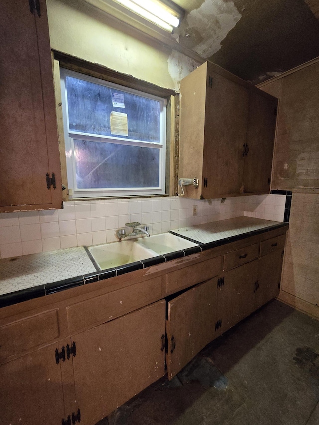 kitchen featuring tile countertops, a sink, and backsplash