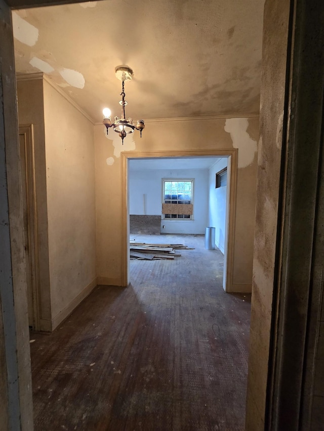 hall with wood finished floors, crown molding, and an inviting chandelier