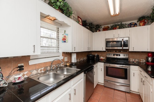 kitchen featuring white cabinets, a textured ceiling, stainless steel appliances, and a sink