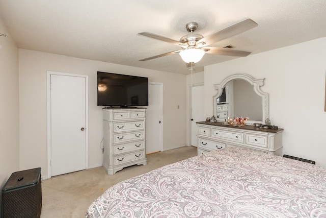 bedroom featuring light carpet, a textured ceiling, and ceiling fan