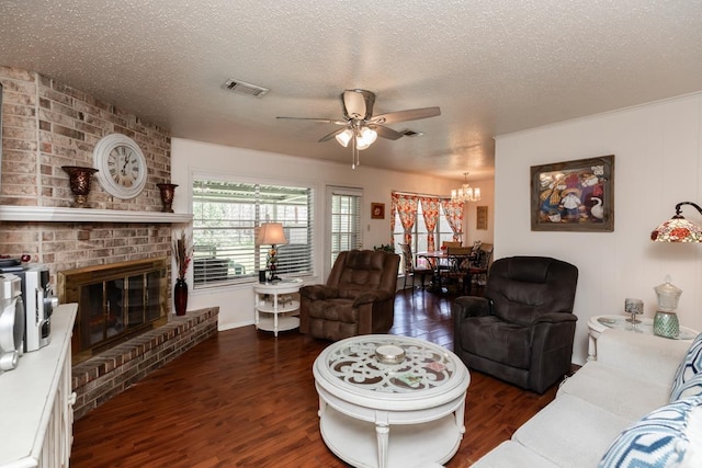 living room featuring ceiling fan with notable chandelier, wood finished floors, visible vents, and a textured ceiling