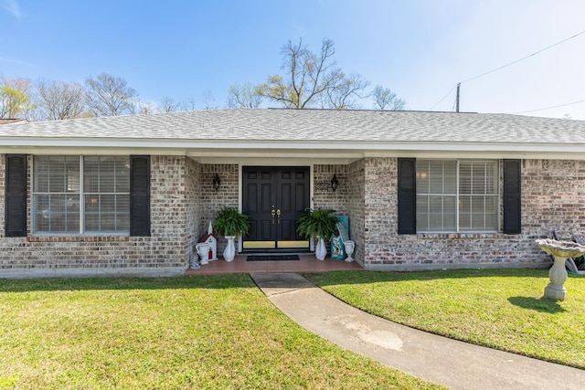 doorway to property featuring a lawn and brick siding