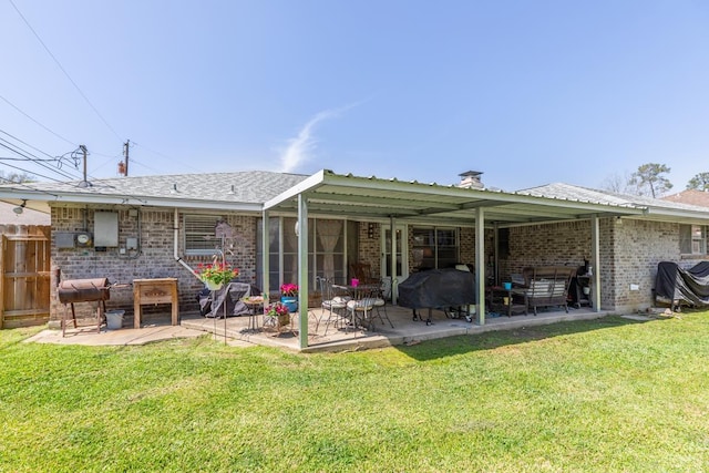 rear view of house featuring brick siding, a lawn, and a patio area