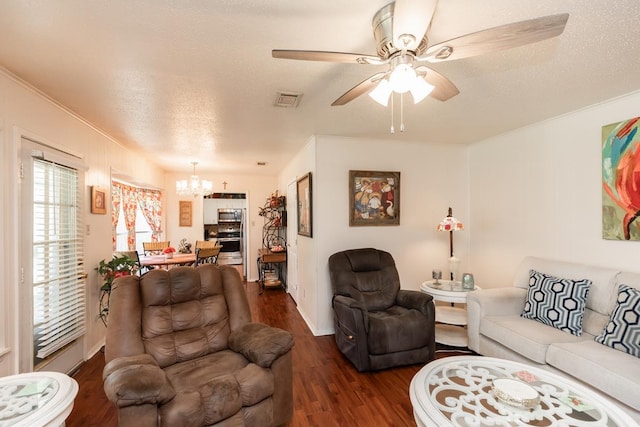 living area with visible vents, ornamental molding, ceiling fan with notable chandelier, dark wood-style floors, and a textured ceiling