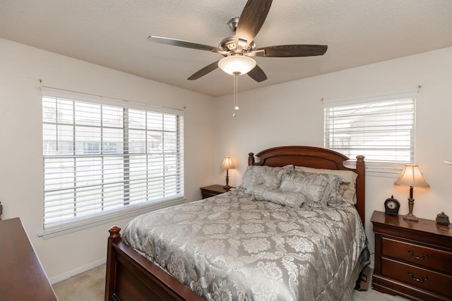 bedroom featuring a textured ceiling, a ceiling fan, baseboards, and light carpet