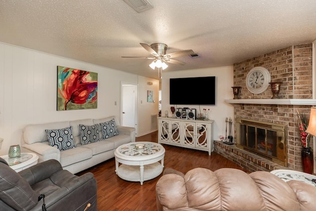 living room with a textured ceiling, wood finished floors, visible vents, and ceiling fan