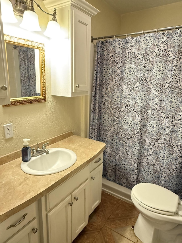 bathroom with vanity, tile patterned floors, toilet, and a textured wall