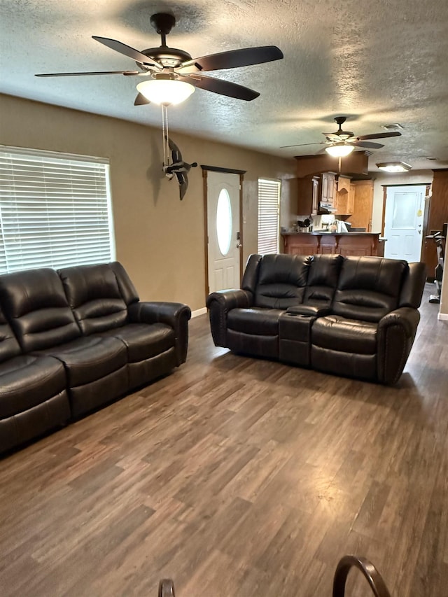 living area with dark wood-type flooring, baseboards, and a textured ceiling