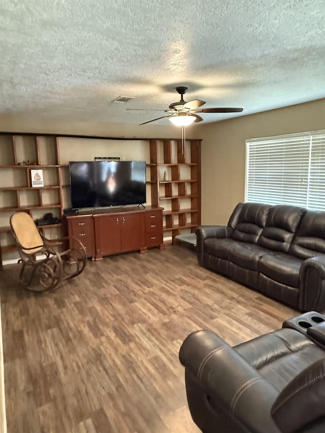 living area with visible vents, a textured ceiling, a ceiling fan, and wood finished floors