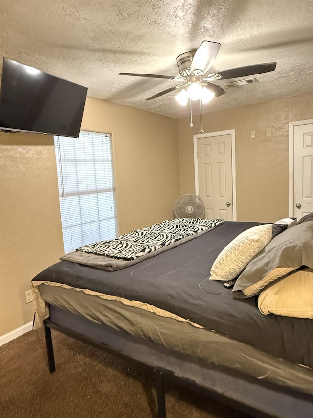 carpeted bedroom featuring a ceiling fan, baseboards, and a textured ceiling